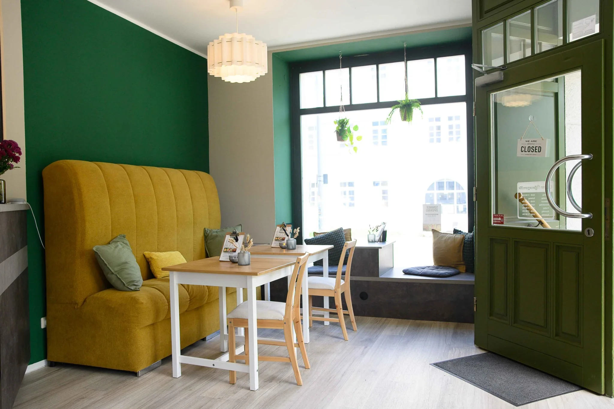 Innenraum des nouri. Cafés mit grüner Wand, gelber Sitzbank und Fensternische